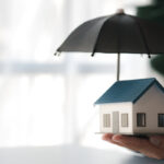 Individuals holding small umbrellas and model homes, housing ins