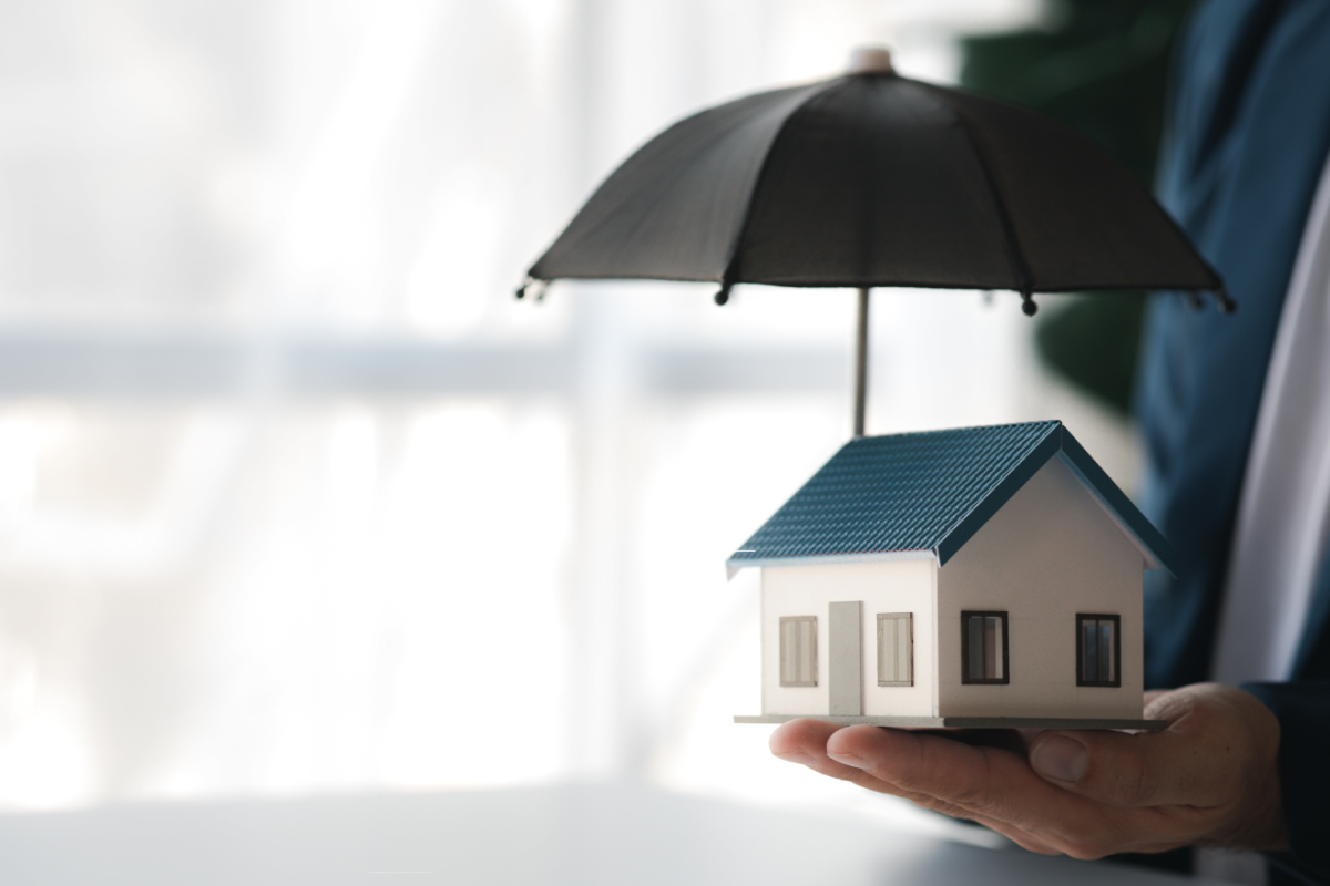 Individuals holding small umbrellas and model homes, housing ins
